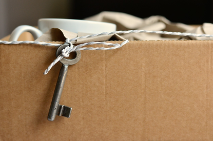 photo d'un carton de déménagement rempli et d'une clé d'appartement posé dessus