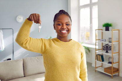 Étudiante souriante tenant les clés de son nouveau logement après un déménagement réussi