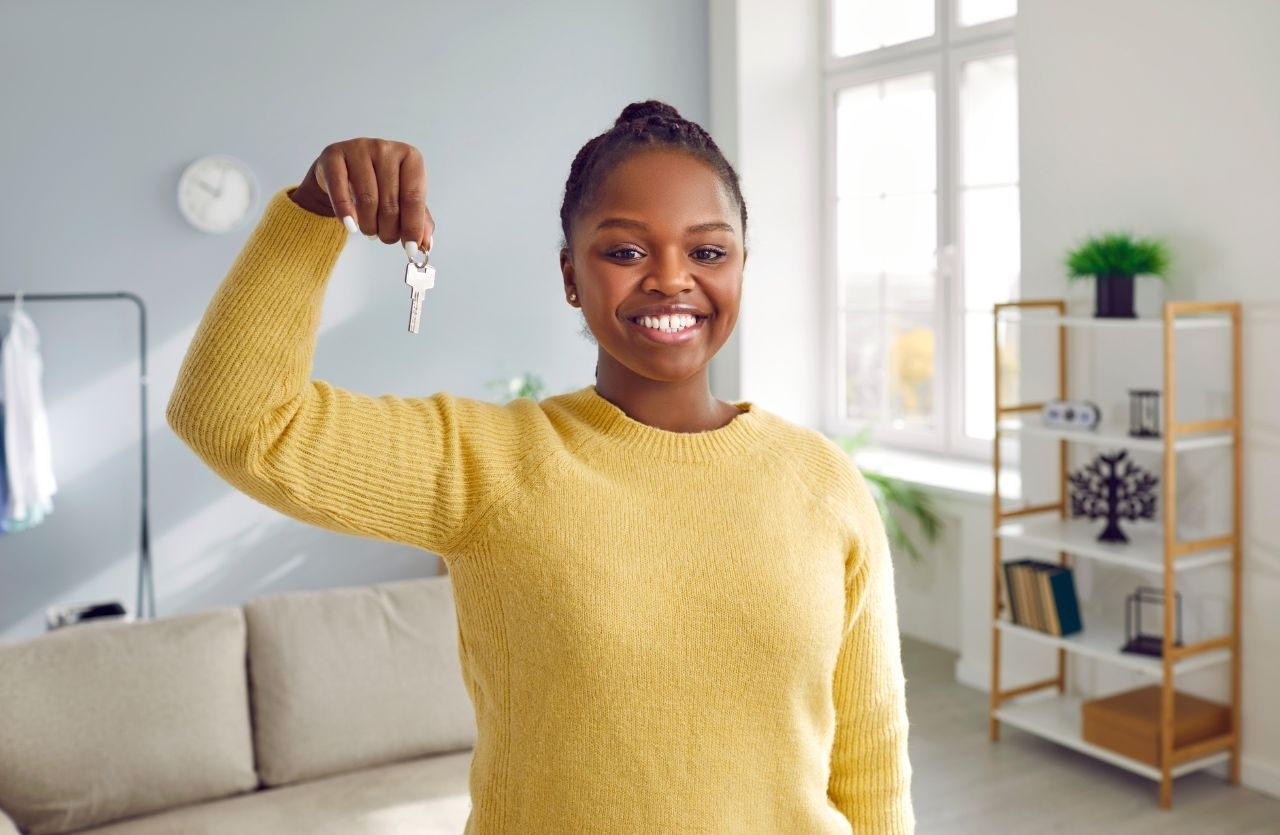 Étudiante souriante tenant les clés de son nouveau logement après un déménagement réussi